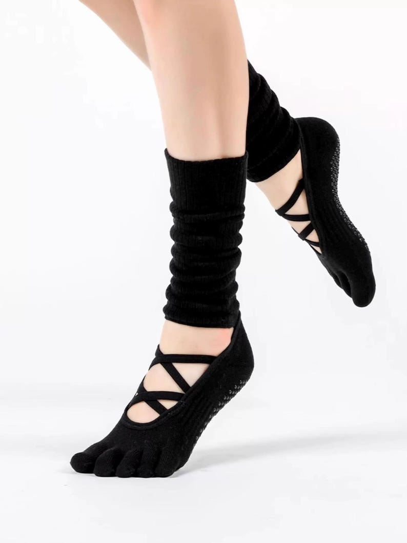 May include: Black yoga socks with crisscross straps and a toe separator. The socks have a non-slip grip on the soles and are designed to be worn during yoga or Pilates. The socks are made of a soft, stretchy material.