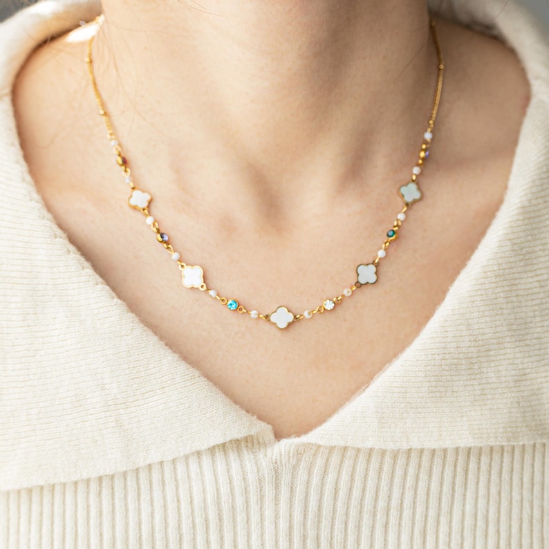 May include: A gold chain necklace with white clover charms and small blue and green gemstones.