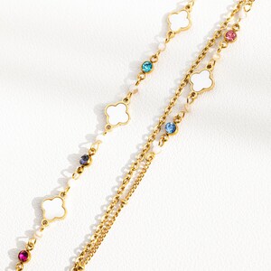May include: A gold chain necklace with white clover charms and colorful crystal accents.