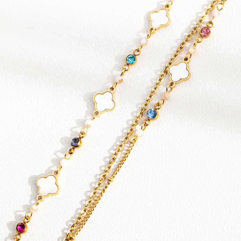 May include: A gold chain necklace with white clover charms and colorful crystal accents.