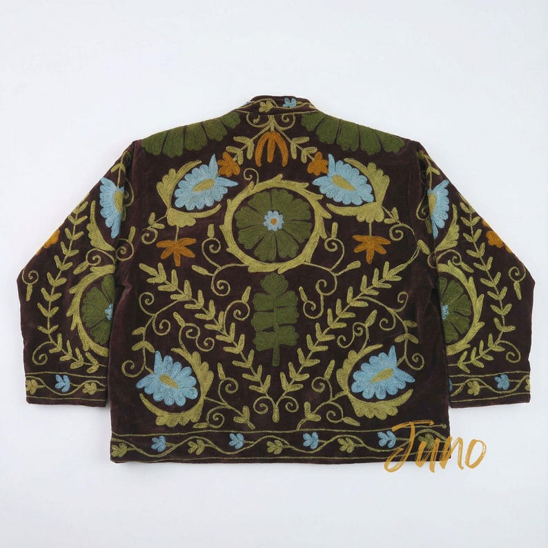 May include: A brown jacket with intricate floral embroidery in shades of green, blue, and orange. The jacket features a round collar and long sleeves. The embroidery is detailed with leaves and flowers, creating a decorative pattern.