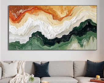 May include: Abstract painting with a layered design of orange, white, and green hues. The painting is displayed on a wall above a gray sectional sofa with pillows and a throw blanket.