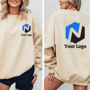 May include: A beige sweatshirt with a blue and black logo and the text "Your Logo" on the front and back. The sweatshirt is a relaxed fit, with long sleeves. The logo is a geometric design.