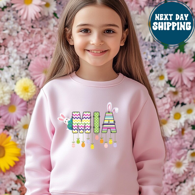 a little girl wearing a pink sweater with a llama on it