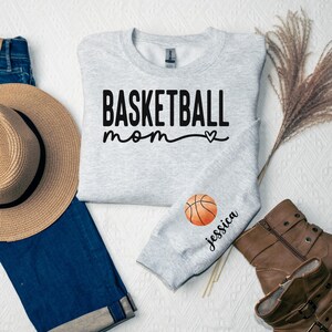 a t - shirt that says basketball mom next to a hat, gloves, and