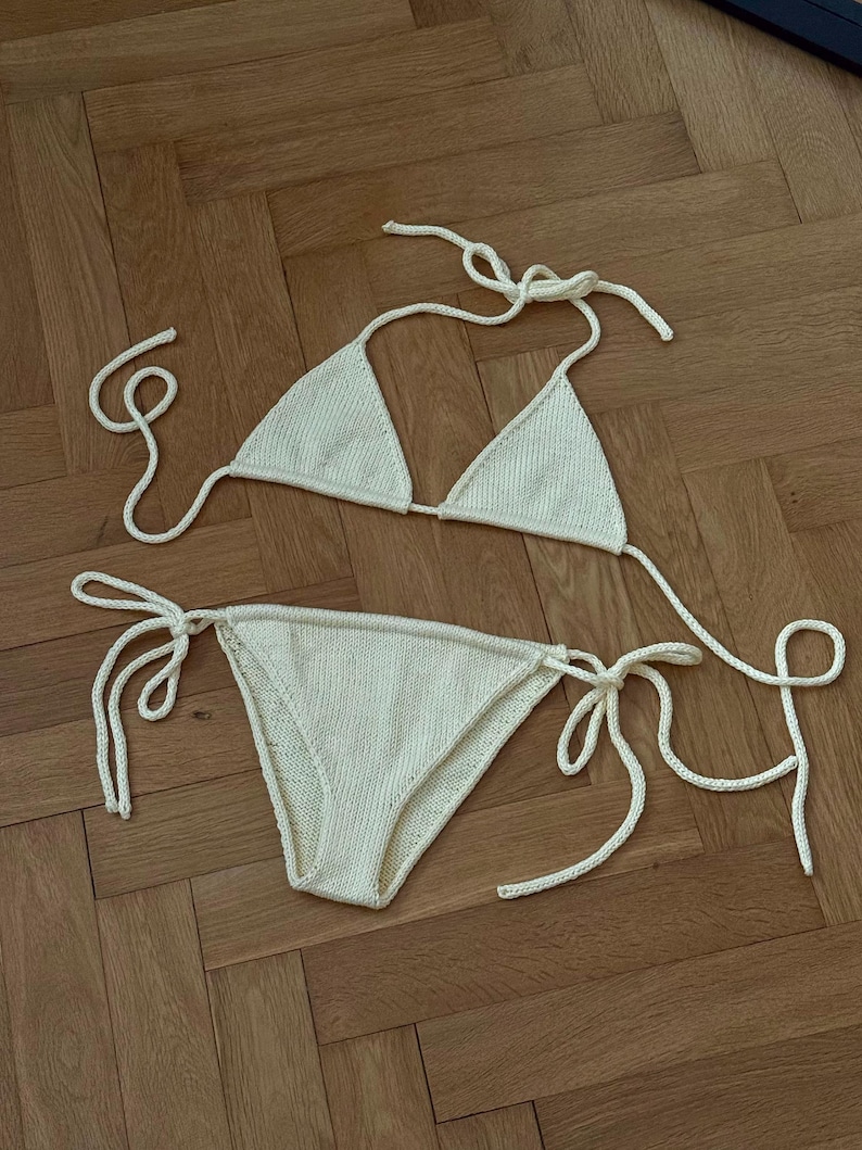 May include: Cream-colored knitted bikini set. The triangle top and low-rise bottoms feature tie closures. The swimwear is made of a textured, soft material, perfect for a beach or poolside look.
