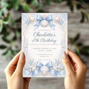 May include: A light blue and beige birthday invitation with seashell and bow illustrations. The invitation reads "Charlotte's 8th Birthday" with event details. The invitation is held by a person.