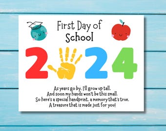 May include: A white card with the text "First Day of School 2024" in colorful letters. A handprint is in the middle of the card. The card also has a small drawing of a globe with a graduation cap and a red apple with a smiling face.