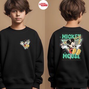 May include: Black sweatshirt featuring Mickey Mouse. The front has a small graphic of Mickey in a triangle. The back displays "Mickey Mouse" in a retro font with Mickey Mouse in the center. The design includes green, yellow, red, and black.