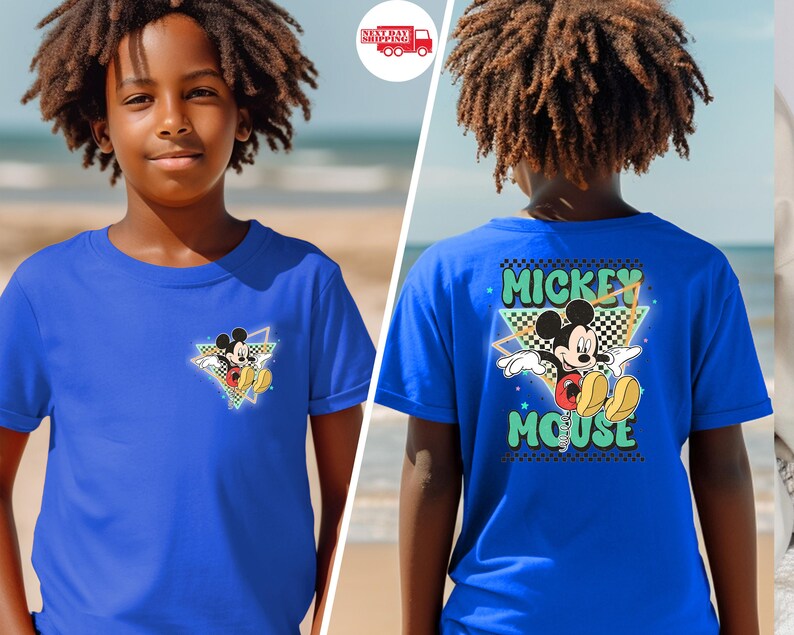 May include: Royal blue t-shirt featuring Mickey Mouse. The front has a small graphic of Mickey in a triangle, while the back displays "Mickey Mouse" in a retro font with a checkered background. The shirt is short-sleeved.
