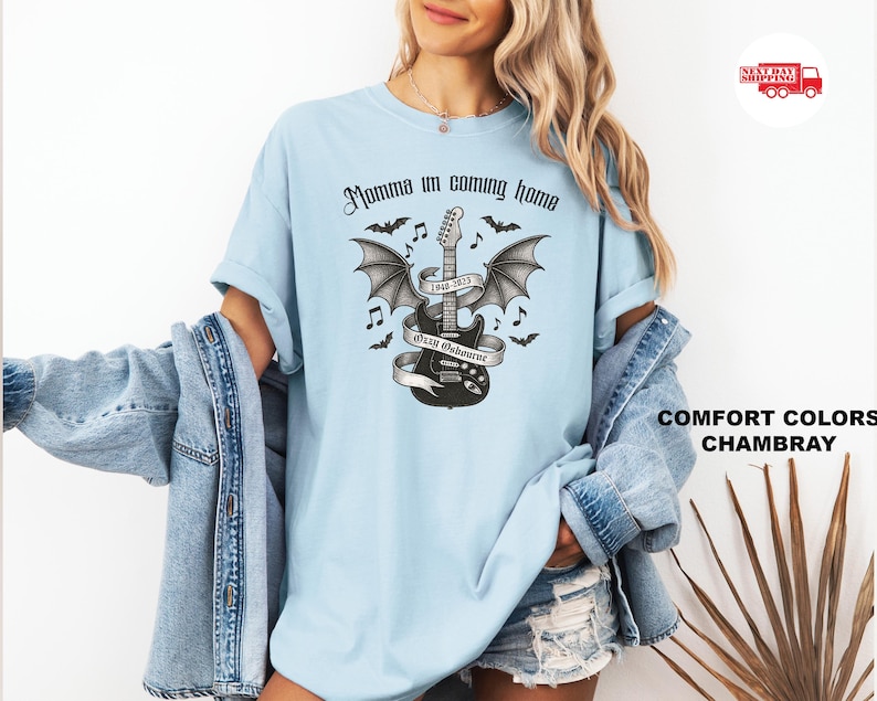 Puede incluir: Camiseta azul claro con un gr&aacute;fico en blanco y negro de una guitarra con alas de murci&eacute;lago, notas musicales y el texto "Momma I'm coming home" y "Ozzy Osbourne". La camiseta est&aacute; hecha de un material suave y c&oacute;modo.