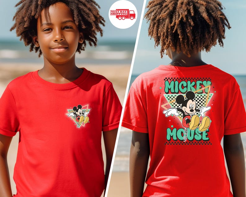May include: Red t-shirt featuring Mickey Mouse. The front has a small graphic of Mickey in a triangle with a checkered background. The back of the shirt has a larger Mickey Mouse graphic with the words "Mickey Mouse" in a retro font.
