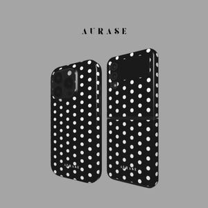 Peut inclure: Deux coques de téléphone avec un fond noir et des pois blancs. Les coques sont pour différents modèles de téléphones. Le mot "AURASE" est imprimé en police sans empattement en haut et en bas des coques.