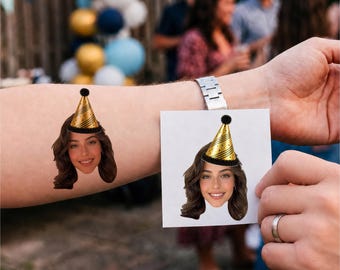 May include: A temporary tattoo on an arm and a square paper print, both featuring the same portrait of a person with brown hair wearing a gold party hat with black polka dots and a black pom-pom on top, set against a blurred outdoor background.