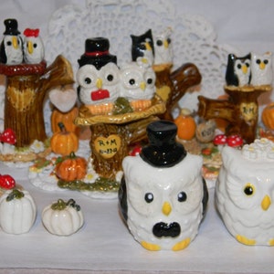 May include: Set of owl figurines dressed as a bride and groom, with a top hat and veil. The owls are perched on tree stumps with pumpkins and fall leaves. The text "R+M 8-27-14" is on one of the stumps.
