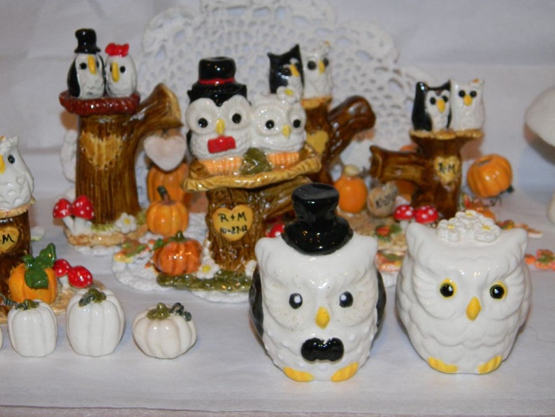 May include: Set of owl figurines dressed as a bride and groom, with a top hat and veil. The owls are perched on tree stumps with pumpkins and fall leaves. The text "R+M 8-27-14" is on one of the stumps.
