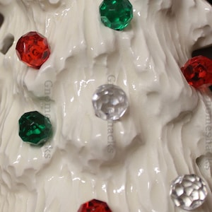 May include: White ceramic Christmas tree ornament with red, green, and clear glass beads. The beads are in a variety of shapes and sizes.
