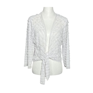 May include: White ruffled cardigan with a tie front. The cardigan is made of a lightweight fabric and has a relaxed fit.