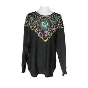 May include: Black sweater with a large, colourful, sequined floral design on the front. The sequins are in shades of gold, silver, blue, green, red, and pink.