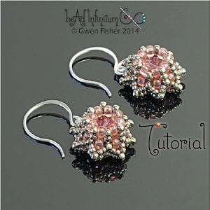 Puede incluir: Un par de pendientes de plata con racimos de cuentas rosas y plateadas. Los pendientes tienen forma de estrella y un diseño colgante.