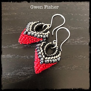May include: A pair of red, black, and silver beaded earrings with silver hooks. The earrings are shaped like a teardrop with a small circle in the center.
