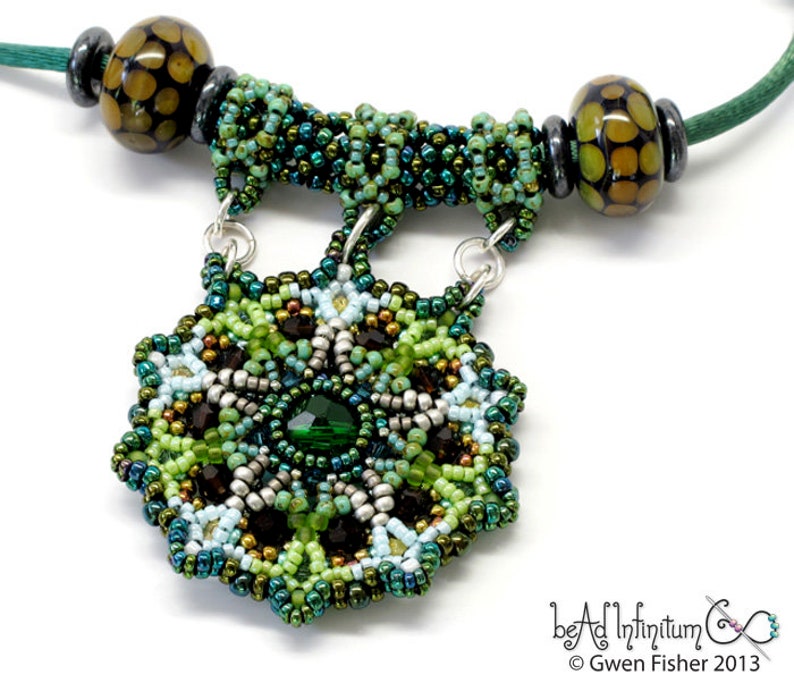 May include: A green, brown, and silver beaded necklace with a large, intricate, beaded pendant. The pendant features a green gemstone in the center and is surrounded by smaller beads in various shades of green, brown, and silver.