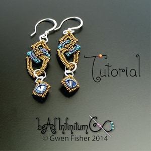 Puede incluir: Un par de pendientes de cuentas doradas y azules con una gota de cristal. Los pendientes están hechos a mano y presentan un diseño único. Los pendientes están etiquetados como "bead infinitum" y "Gwen Fisher 2014".