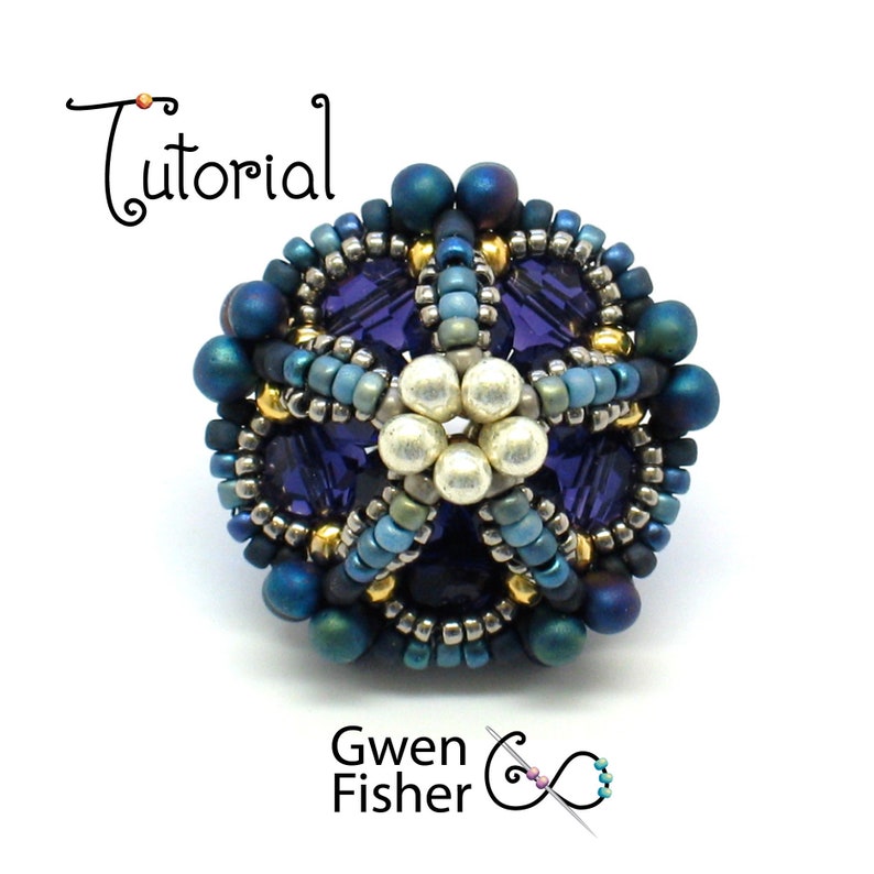 May include: A close-up of a beaded flower pendant with a blue, purple, and gold color scheme. The pendant is made with seed beads and features a central flower design with a pearl center.
