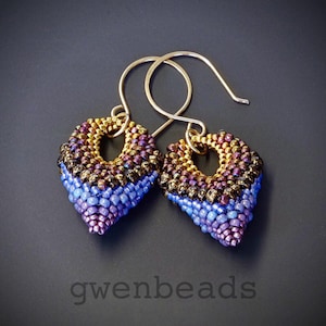 May include: A pair of gold-toned earrings with a teardrop shape. The earrings are made of small beads in shades of gold, brown, blue, and purple.
