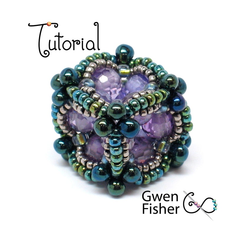 May include: A beaded cube with a geometric design. The cube is made with purple, green, and silver beads. The cube is a jewelry piece.