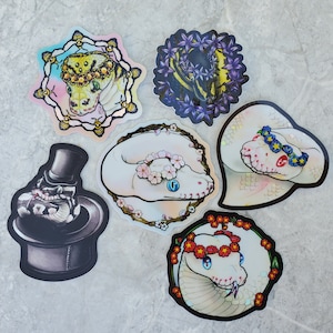 Op de afbeelding: Zes kleurrijke stickers met verschillende slangontwerpen. De stickers tonen een slang met een kroon, een slang met bloemen, een slang met een hoed en een slang met een bloemenkrans. De stickers zijn perfect om een vleugje whimsy toe te voegen aan je laptop, waterfles of planner.