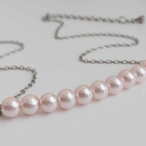May include: A delicate silver chain necklace with a row of eight pale pink pearls.