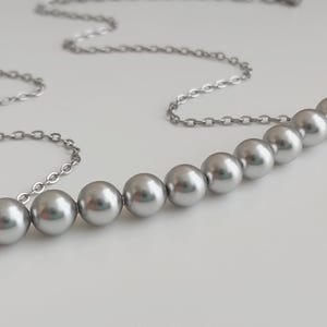 May include: A silver chain necklace with a row of seven silver pearls.