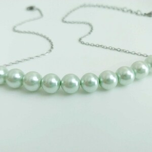 May include: A silver chain necklace with a row of light green pearl beads.
