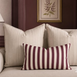 May include: Two large square throw pillows in a light beige fabric with a subtle vertical stripe pattern, paired with one smaller rectangular lumbar pillow featuring bold, vertical dark burgundy and beige stripes, measuring 20 inches by 14 inches.