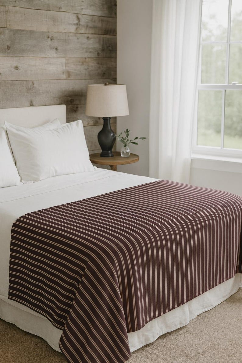 Soft maroon striped throw blanket texture on a bed