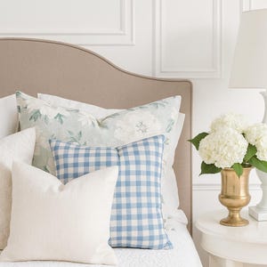 Feminine blue gingham pillow on a modern classic bedroom