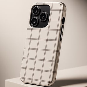 May include: A phone case with a cream-colored background and a grid pattern of thin, dark gray lines. The case has a glossy finish and a black camera module with three lenses. The phone case is displayed on a white surface.