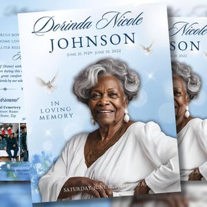 May include: A memorial card featuring a portrait of Dorinda Nicole Johnson, with dates June 21, 1929 - June 10, 2022. The card has a light blue background with doves and the words "In Loving Memory".