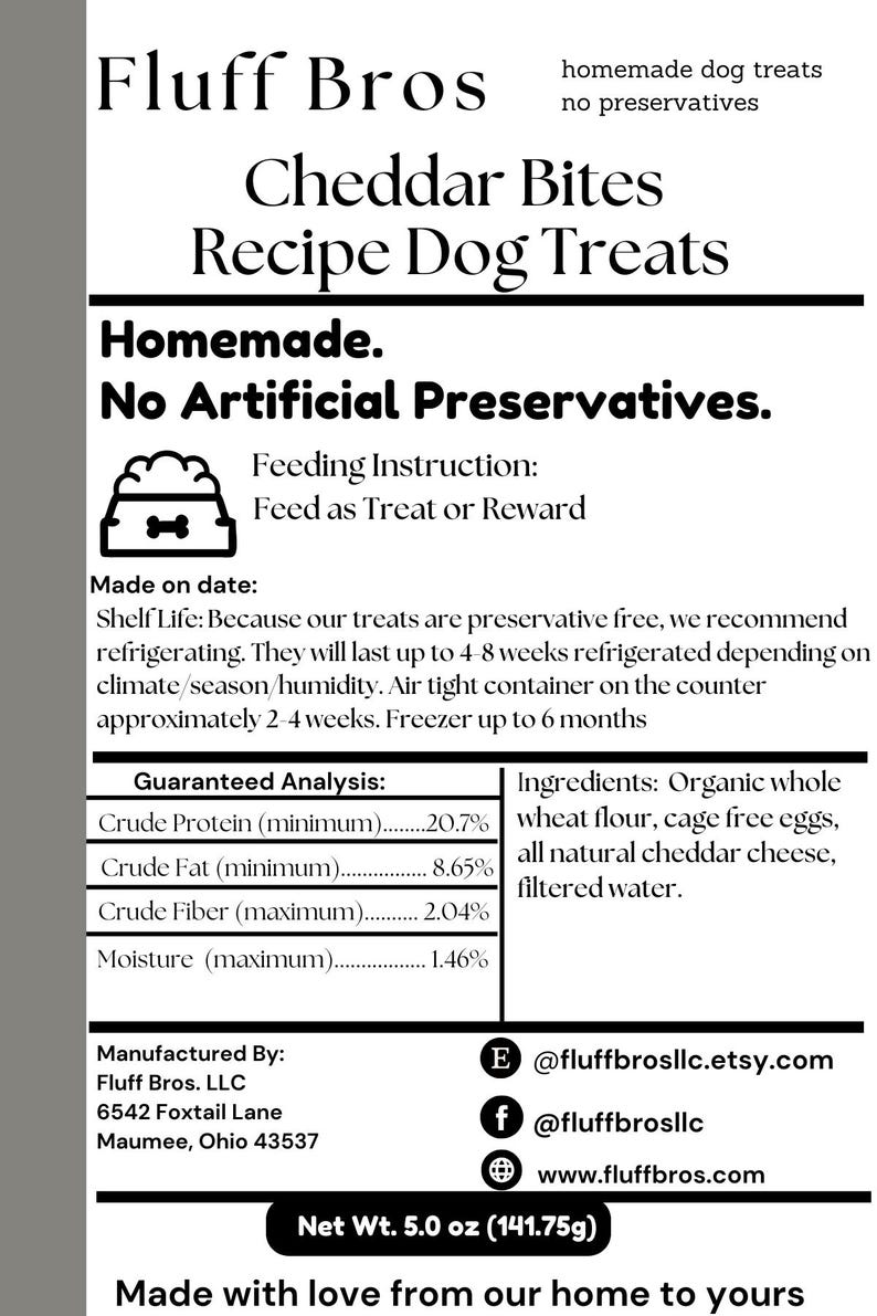 May include: A white label with black text for homemade dog treats called "Fluff Bros Cheddar Bites Recipe Dog Treats". The label states "Homemade. No Artificial Preservatives." and includes a guaranteed analysis of the ingredients, a list of ingredients, and contact information for the company. The label also states "Net Wt. 5.0 oz (141.75g)" and "Made with love from our home to yours".