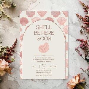 Könnte beinhalten: Eine Babyparty-Einladung mit Muschel-Design. Die Einladung zeigt den Text "SHE'LL BE HERE SOON" in einer eleganten Schriftart. Das Design umfasst Muschel-Illustrationen und Veranstaltungsdetails für die Babyparty.