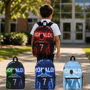 May include: A collection of four backpacks featuring a graphic of a football player wearing a jersey with the name RONALDO and the number 7. The backpacks are available in red, green, blue, and light blue colourways, each with a front zippered pocket.