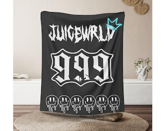 May include: A black rectangular throw blanket featuring the white text JUICEWRLD at the top with a light blue crown icon. Below is the large white number 999 in a stylized font, followed by a row of six white dripping smiley face graphics.