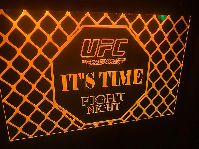 May include: A black and orange sign with the UFC logo and the text "It's Time Fight Night".