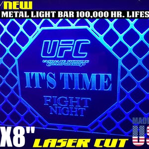May include: A blue and white 12x8 inch laser cut metal light bar with the UFC logo and the text "It's Time Fight Night".