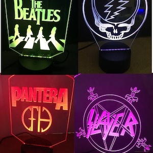 以下が含まれることがあります： 黒いベースの4つのアクリル照明ランプ。ランプには、The Beatles、Grateful Dead、Pantera、Slayerのロゴが描かれています。各ランプは、緑、白、赤、紫の異なる色で光ります。