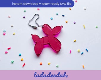 May include: Pink balloon animal keychain charm in the shape of a dog. The charm is made of acrylic and has a silver chain attached.