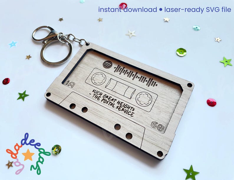 May include: A wooden cassette tape keychain with a silver keyring. The cassette design includes the text "SUCH GREAT HEIGHTS - THE POSTAL SERVICE" and a sound wave graphic. The keychain is laser-ready and an instant download.