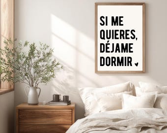 Può includere: Una stampa da parete rettangolare in una cornice di legno chiaro con il testo nero SI ME QUIERES, DÉJAME DORMIR e un piccolo simbolo a forma di cuore nero su sfondo bianco, esposta sopra un letto con biancheria bianca e un comodino in legno.