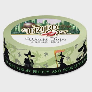 May include: A roll of washi tape featuring a design from The Wizard of Oz. The tape has a light green background with silhouettes of the Wicked Witch and flying monkeys. The top of the tape features the movie title and ruby slippers.